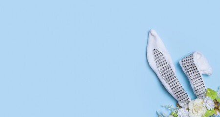 Easter banner with bunny ears and flowers, easter eggs top view on blue background. Copy space