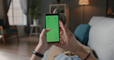 Close up shot of person relaxing on sofa and using smart phone with mock up green screen, doing various gestures - technology, communication