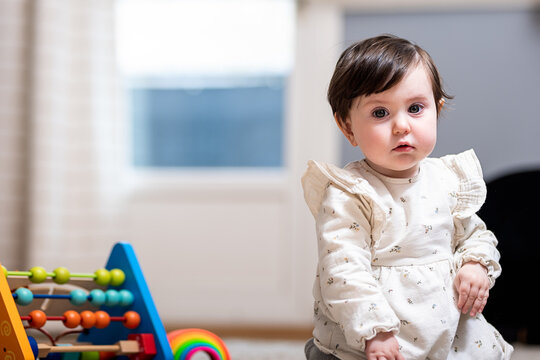 Cute little girl near abacus toy at home