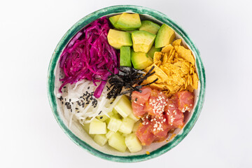 Bowl with tuna, avocado, red cabbage, nachos, cucumber, nori, white and black sesame seeds. Round green bowl on a white background. Top view.