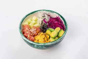 Bowl with tuna, avocado, red cabbage, nachos, cucumber, nori, white and black sesame seeds. Round green bowl on a white background. Close up 3/4