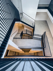 view from above into a stairwell of a multi-storey residential building with black steel railings
