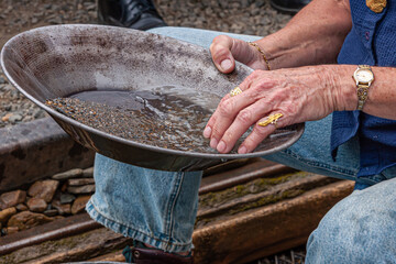 Fox, Alaska, USA - July 26, 2011: Eldorado Gold Mine museum and park. Closeup of female hands using a pan to separate gold dust from sand and small pebble by washing.