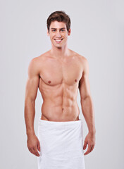Fototapeta premium Killer looks and abs. Studio shot of a bare-chested young man with a towel wrapped around his waist.