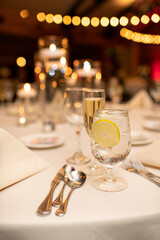 Close up of Lemon Water and Modern Dinner Table Setting at Event with Lights and Candles