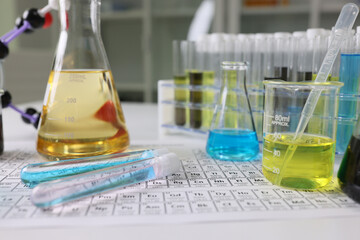 Research laboratory glassware with reagents on periodic table of chemical elements.