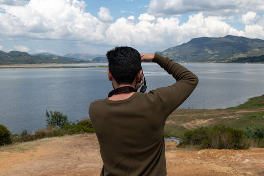 hombre tomando fotografía con cámara profesional con fondo de lago y montañas 