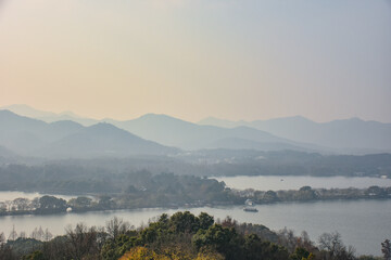 High angle view of the calm seascape and mountains in the cloudy weather. Travel rural scene. West Lake. Popular park of Hangzhou city China.