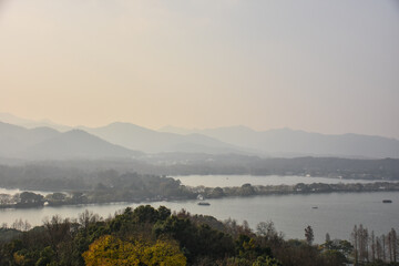 High angle view of the calm seascape and mountains in the cloudy weather. Travel rural scene. West Lake. Popular park of Hangzhou city China.