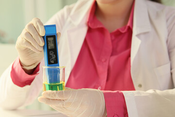 Close-up of scientist measuring properties of liquid sample.
