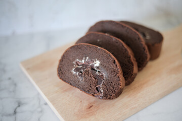 Chocolate roll cake slice with vanilla cream and dark compound chocolate. Sweets dessert cream roll chocolate snacks and food concept. Swiss Roll Cake, Cake roll on wooden