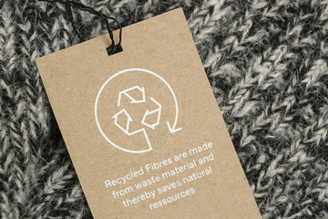 Close up of clothing tag with recycle icon. Recycling products concept. Zero waste, suistainale production, environment care and reuse concept. - obrazy, fototapety, plakaty