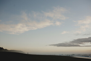 Person standing on the beach admiring sunset