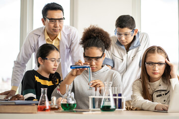 Fototapeta na wymiar Diversity group of students in protective eyeglasses in science class doing chemical experiment in laboratory. Teacher watching girl mixing chemistry in test tube. learning and education concept