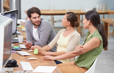 Working together to make the project a success. a group of young businesspeople talking at their desk.