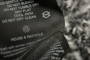 Fabric composition label, Washing instructions and recycling sign on black fabric label. Laundry...