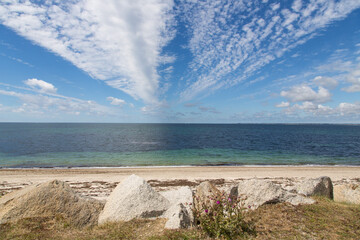 Stones and beautiful cloudy sky, the atlantic ocean with clear turquoise water and a sandy beach-...