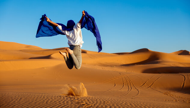Woman tourist jumping in the Sahara desert - Powered by Adobe