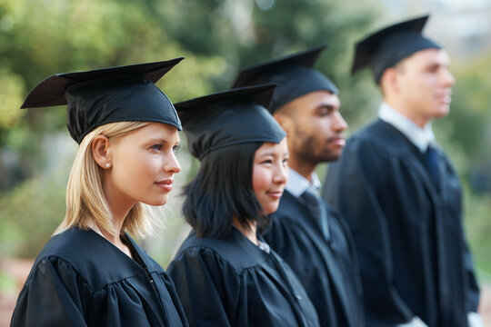 Looking forward to a bright future. Young college graduates holding their diplomas while standing in a row.