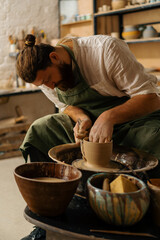 Obraz na płótnie Canvas A potter sculpts a jug on a potter's wheel in a pottery workshop