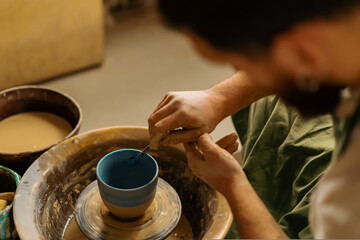 Fototapeta na wymiar Pottery workshop potter paints a jug with a brush and paint on a potter's wheel