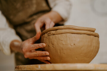 In the pottery workshop the master sculpts clay dishes with his hands on the table