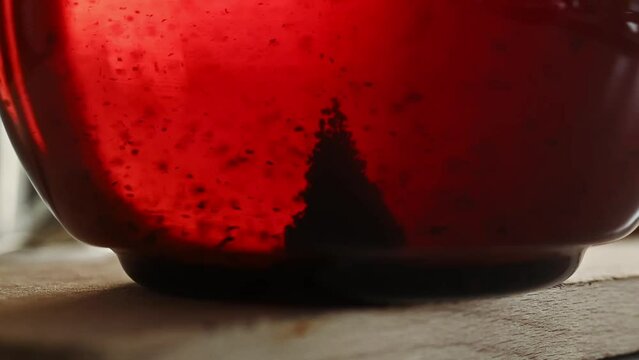 Black tea in transparent kettle during stiring closeup. Hot natural herbal beverage in kettle