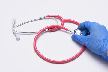 Lekarz trzymający czerwony stetoskop w dłoni w rękawiczce  - obrazy, fototapety, plakaty