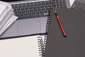 Laptop, notes, długopis i stos dokumentów - biurko w pracy