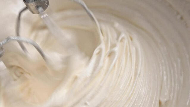 Creamy mixing with automatic mixer closeup. Tasty bakery desert cake preparation with homemade recipe