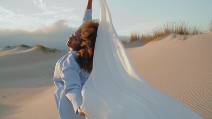 Girl fabric blowing wind at summer desert. Woman posing with white cloth at sand