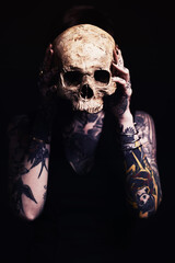 Getting to grips with the grim reaper. Studio shot of a tattooed young woman.