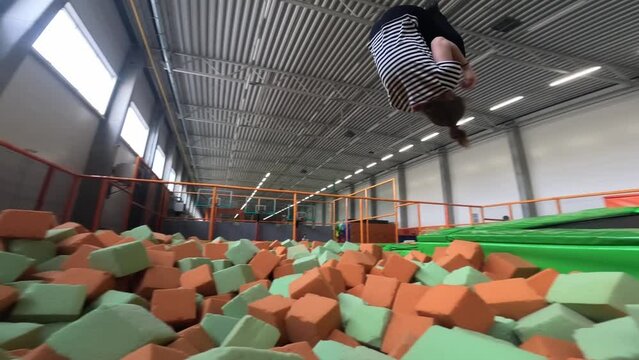 Young teen girl jumping in colorful soft cubes and in trampoline park