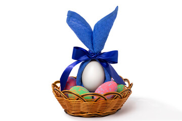 Easter multicolored eggs in a wicker basket with a napkin decoration in the form of rabbit ears.