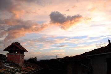Heart shaped cloud over town roofs at sunset.