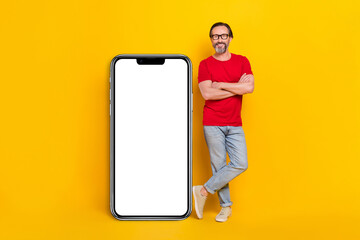 Fototapeta na wymiar Photo of attractive funny retired man wear red t-shirt spectacles arms folded device empty space isolated yellow color background