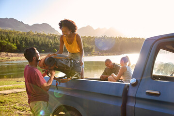 Group Of Friends Unloading Backpack From Pick Up Truck On Road Trip By Lake In Countryside - Powered by Adobe