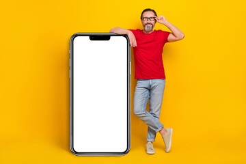 Photo of sweet cute retired man wear red t-shirt spectacles modern device empty space isolated yellow color background