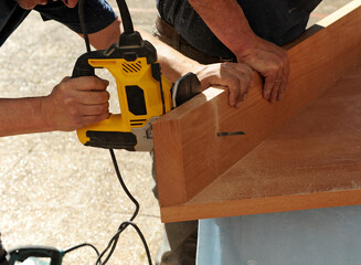 Carpenter cutting with a jigsaw the beech wood stair step of a staircase for the interior of a house 