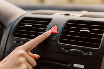 Close up woman press emergency gang red button accident, black dark car interior. Dashboard display...
