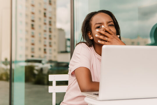 Tired exhausted overworked african american woman hipster sitting outside with laptop yawning. Young entrepreneur freelancer student businesswoman low energy need to sleep have a rest chill
