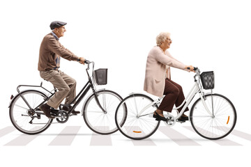 Elderly man and woman riding bicycles at a pedestrian crossing