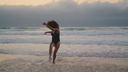 Girl performer dancing beach at cloudy gray sky. Woman moving body in ocean.