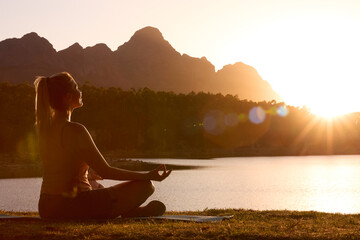 Woman Meditating Doing Yoga By Lake And Mountains At Sunset