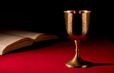 christian chalice with open bible on red background