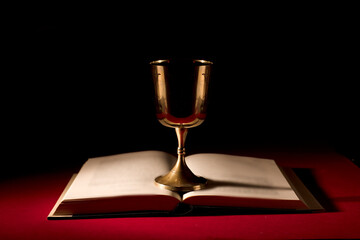 christian chalice on open bible with strong red background