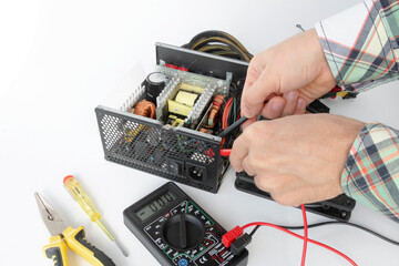 repair of a disassembled Computer Power Supply Unit, tester measurement, on a white background