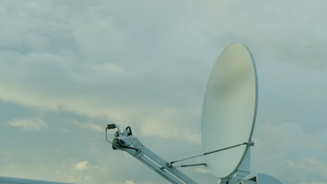 SNG vehicles for TV broadcasting with round white satellite on roof against cloudy sky. Satellite transmits signal of live streaming