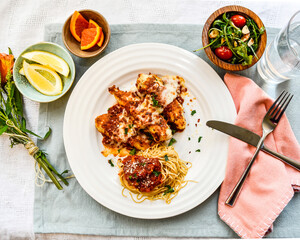 Chicken Parmesan top view with side salad and oranges 