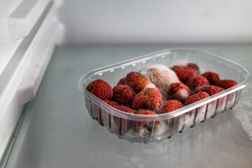Moldy raspberries in a plastic basket inside a refrigerator. Food past its expiration date, spoiled...